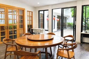 Een ronde houten tafel met zes stoelen in een kamer met grote glazen deuren die uitkomen op een buitenruimte.