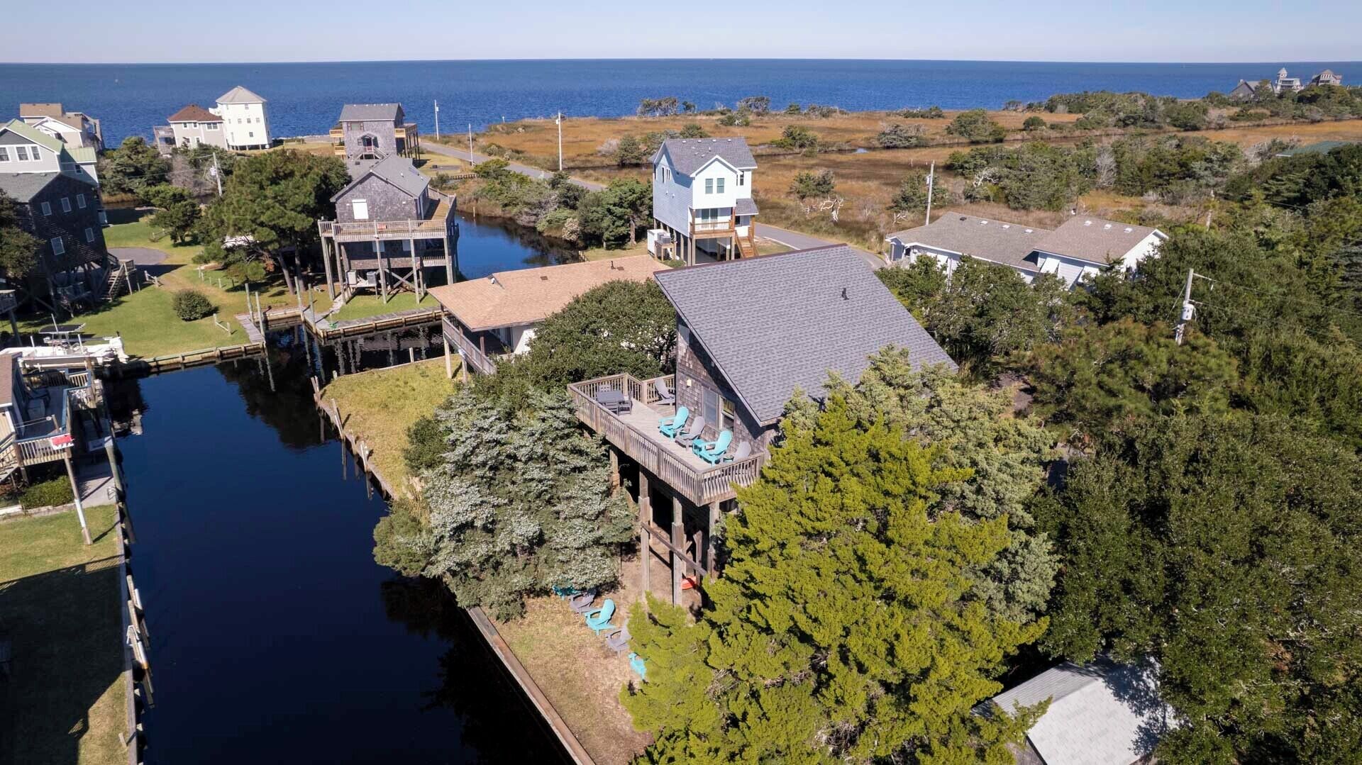 A coastal property with a dock, a small boat, and a house with a deck overlooking the water.
