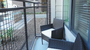 A balcony with wicker furniture, a metal fence, and a view of a building with balconies and windows. - The Blue Pearl Retreat (Houston)