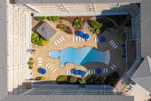 Vue aérienne d’un espace piscine d’hôtel, avec des transats, une piscine et des parterres de jardin aménagés.