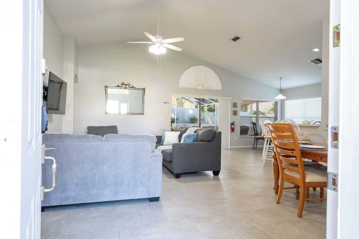 Ein modernes Wohnzimmer mit einer Couch, einem Esstisch mit Stühlen und einem Deckenventilator.