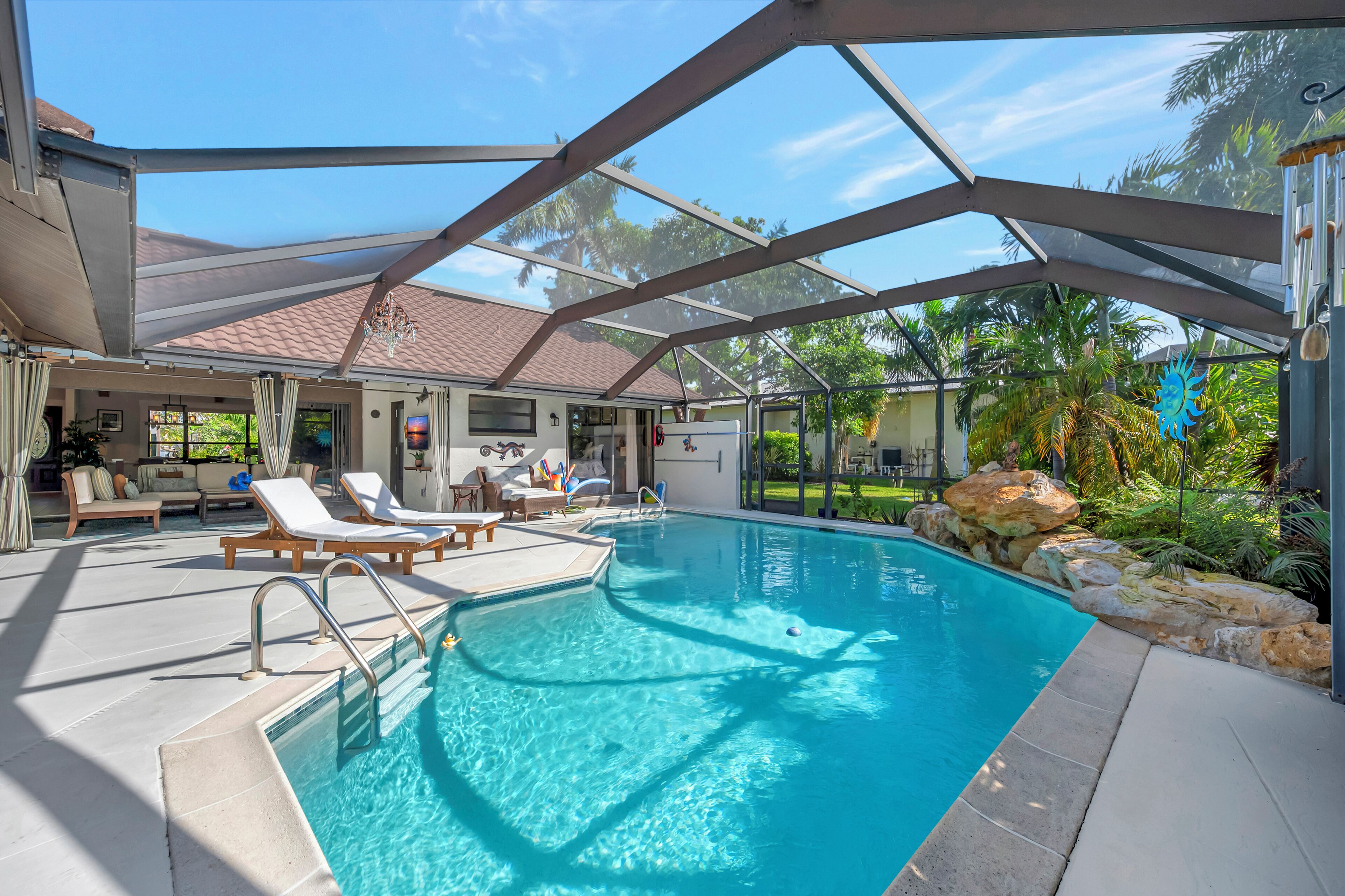 A swimming pool with lounge chairs and a covered patio area.