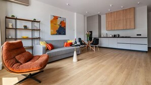 Ein modernes Wohnzimmer mit grauem Sofa, orangenem Sessel und Holzboden.
