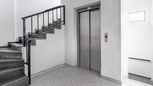 Ein modernes Interieur mit Treppe, Aufzug und einer Tür mit Lichtschalter.
