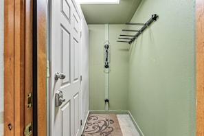 A hallway with a white door, a wooden door frame, a green wall, a ceiling light, and a towel rack. - Ski Hill 39: Ski-In Breck Condo Near Gondola, Fireplace, Ski Locker, Hot Tubs (Breckenridge)