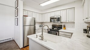 Una cocina moderna con armarios blancos, electrodomésticos de acero inoxidable y encimera de mármol.