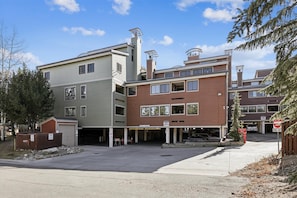 A multi-story residential building with a garage and a covered parking area. - Ski Hill 39: Ski-In Breck Condo Near Gondola, Fireplace, Ski Locker, Hot Tubs (Breckenridge)