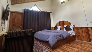 A bedroom with a wooden ceiling, a bed with a headboard, a radiator, and a window with curtains. - Hotel Sno Cottage (Manali)