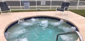 A hot tub with water jets, surrounded by a white fence and two lounge chairs. - Paradise Found at Coastal Myrtle Beach 2B, 2B Condo (Myrtle Beach)