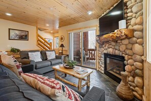 Ein gemütliches Wohnzimmer mit Kamin, Holzboden und Steinwand.