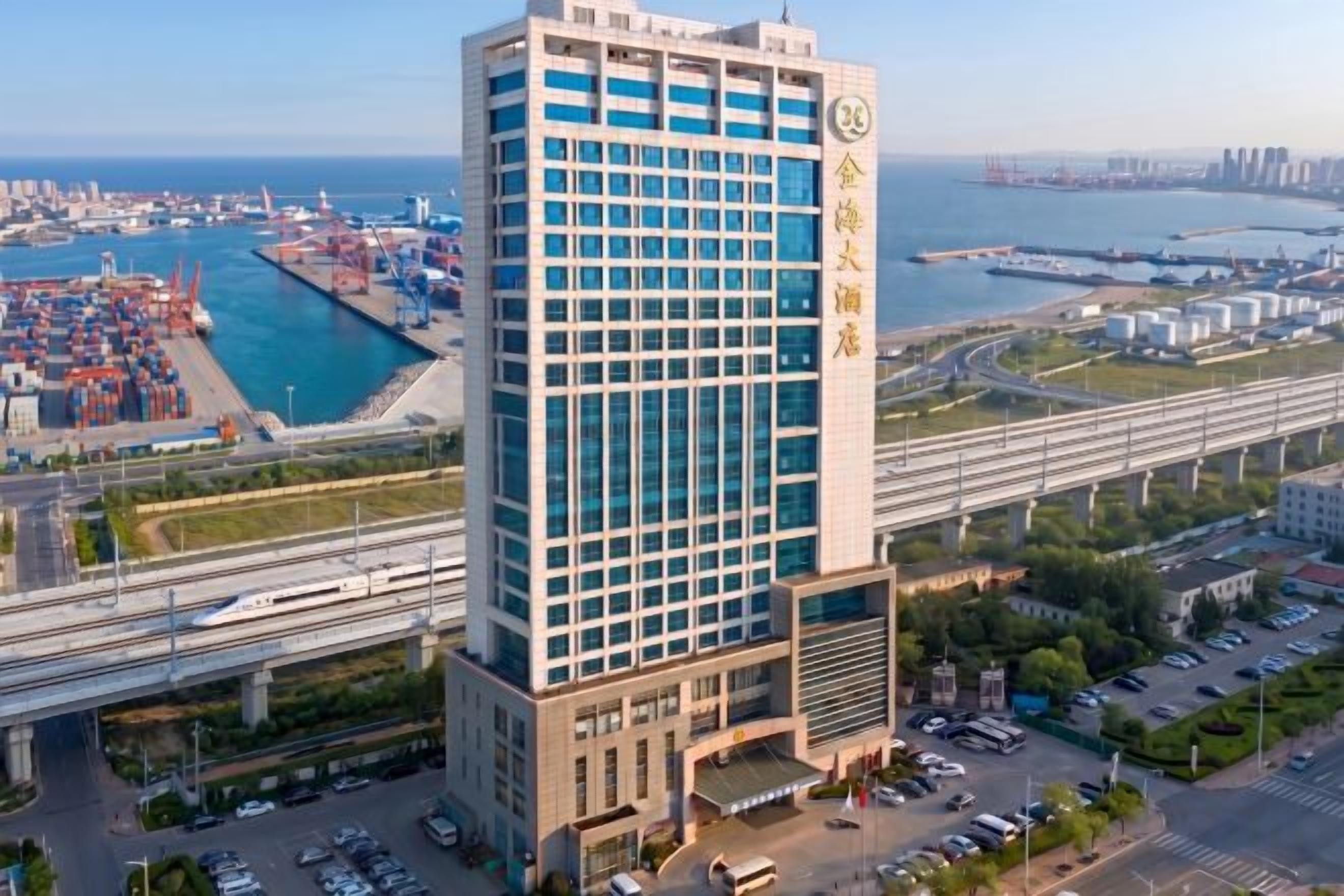 A high-rise hotel with a modern design, located near a body of water and a busy port area.