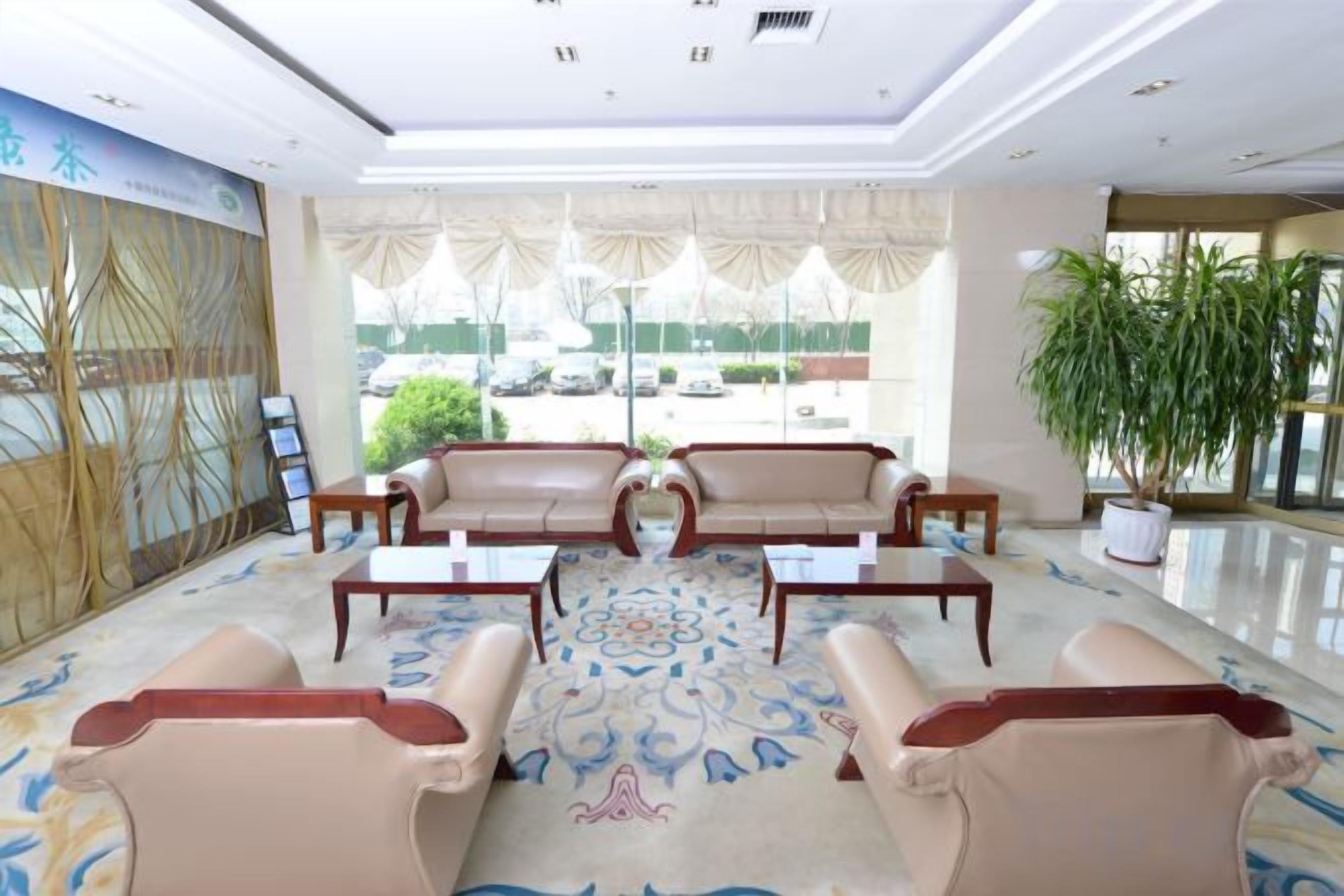 A lobby with leather sofas, a coffee table, and a potted plant.