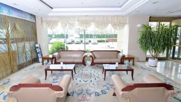 A lobby with leather sofas, a coffee table, and a potted plant.