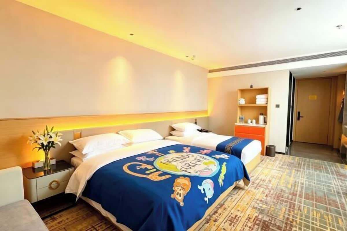 Hotellihuone, jossa on sänky, yöpöytä, lamppu ja toinen pienempi pöytä.
