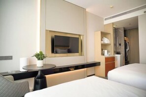 A modern hotel room with a bed, a desk with a plant, a mirror, and a wardrobe.