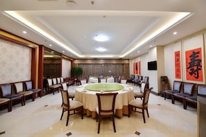 A conference room with a round table, chairs, and a large plant.
