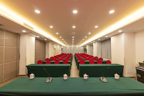 Una sala conferenze con file di tavoli, ognuno dotato di un microfono e una teiera.