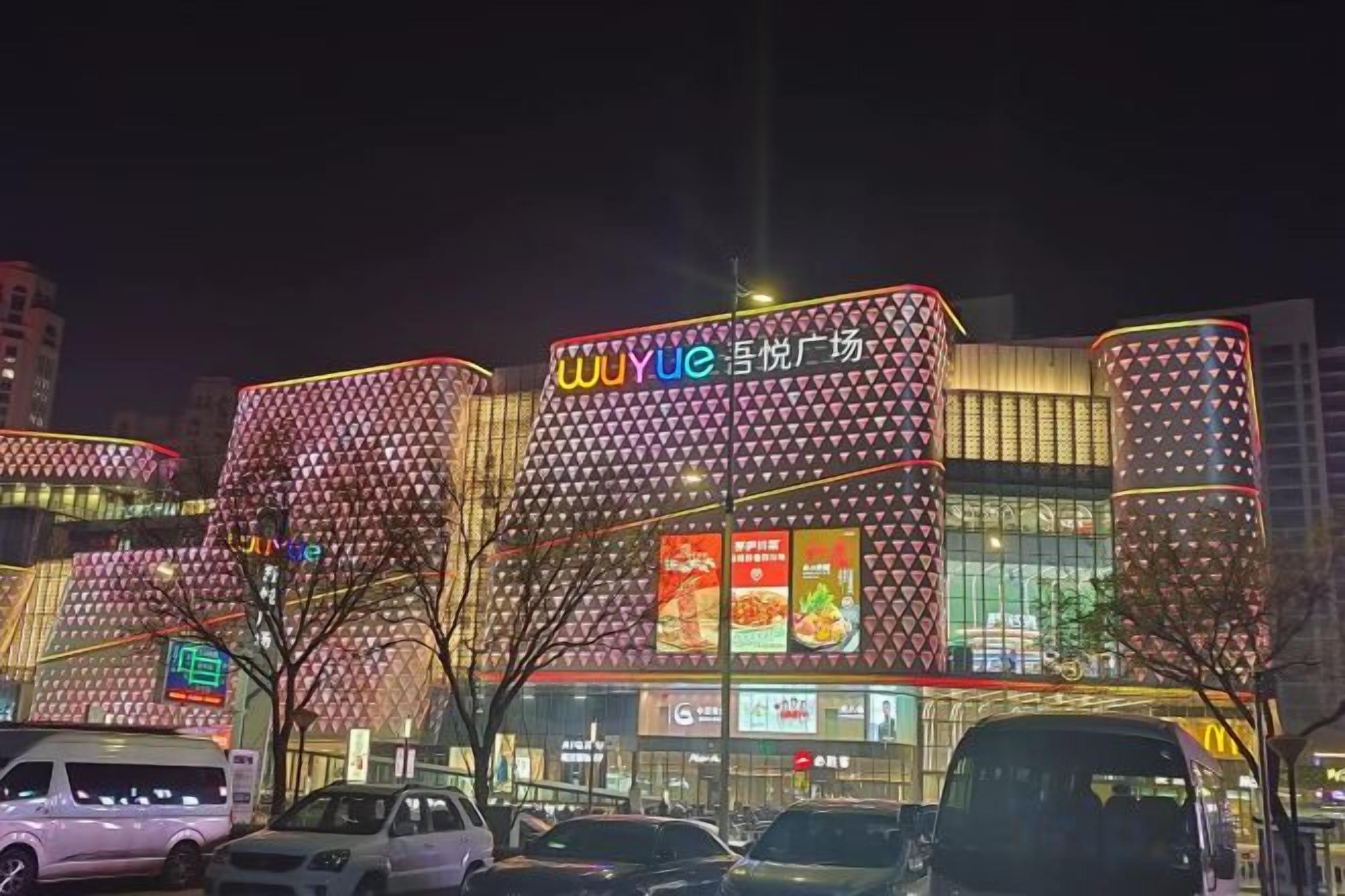 Un edificio de varios pisos con letreros iluminados y un anuncio grande.