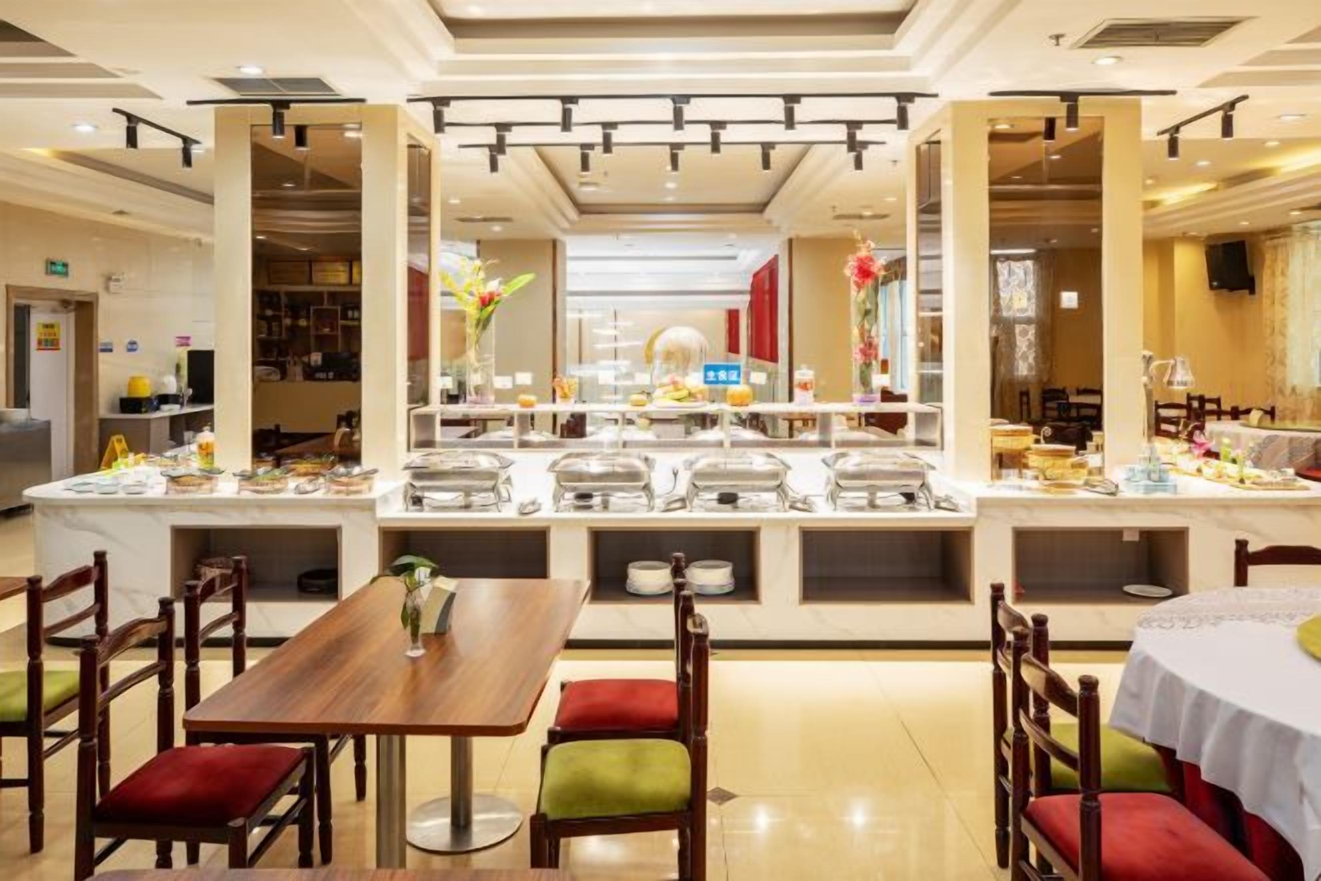 A hotel dining area with multiple tables and chairs, a buffet setup, and a view of the adjacent restaurant.