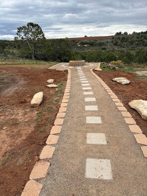 A pathway leading to a circular stone structure surrounded by a gravel area with scattered rocks.