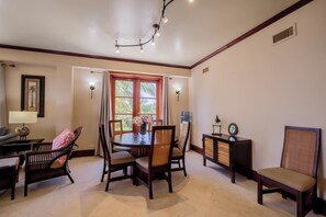 A dining area with a round table, chairs, a water dispenser, and a clock on a cabinet.