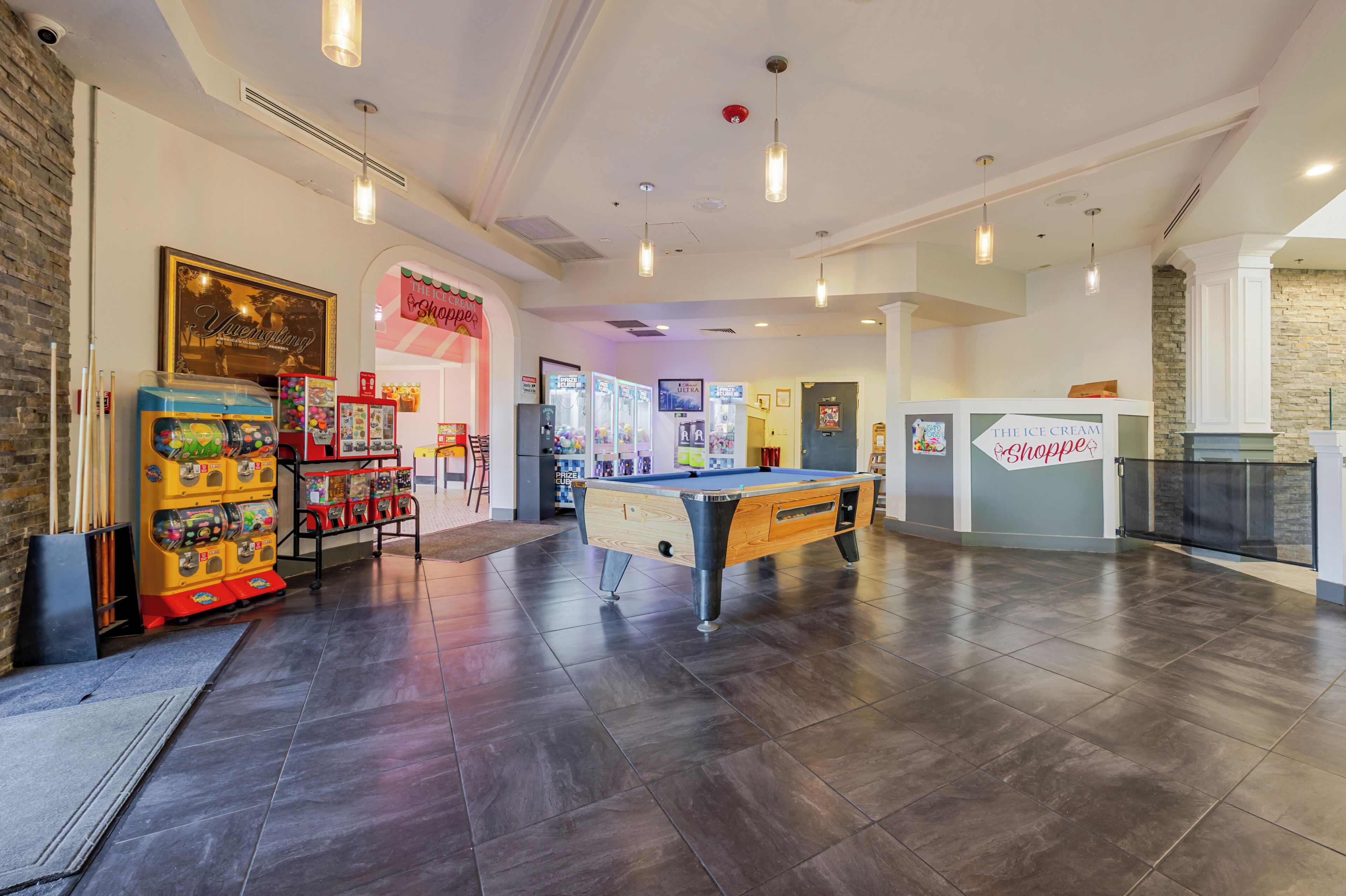 Een ruime binnenzone met een pooltafel, automaten en een bord met daarop 'The Ice Cream Shoppe'.
