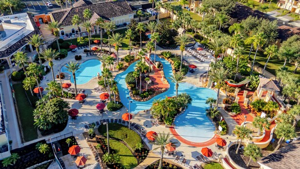An aerial view of a resort with two swimming pools, palm trees, and sun loungers. - Near Disney Regal Palms Renovated Resort-New Pool-Lazy River-Arcade-Kid Friendly (Davenport)