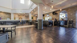 A spacious indoor area with multiple seating arrangements, a central bar area, and a stone accent wall. - Near Disney Regal Palms Renovated Resort-New Pool-Lazy River-Arcade-Kid Friendly (Davenport)