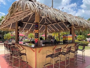 A thatched-roof bar area with wooden chairs and a counter. - Near Disney & Universal Regal Palms Resort with Pools Lazy River and Arcade Fun! (Davenport)