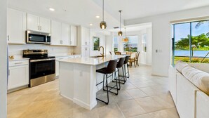 A modern kitchen with white cabinetry, stainless steel appliances, and a central island with bar stools. - Enjoy a luxury 2BR/2BA Condo in beautiful Ave Maria Golf and Country Club (Ave Maria)