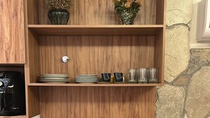 A dining area with a wooden wall, a stone accent wall, and a table set with multiple cups and saucers. - Apartment / Beachfront / Pool / Intermares (Cabedelo)
