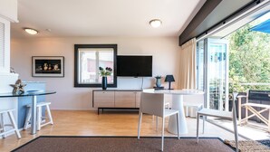 Una cocina moderna con comedor, televisor de pantalla plana y un amplio ventanal con persianas.