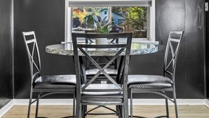 A dining area with a round table and four chairs, a chandelier, and framed pictures on the wall.