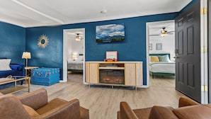 A room with a fireplace, a blue wall, and a bed with green bedding.