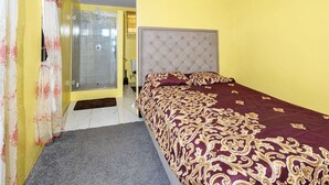 Un dormitorio con cama, ducha y puerta que da a otra habitación.