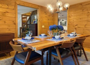 A wooden dining table set with blue and white tableware, surrounded by chairs with blue cushions. - Summit Trail Lodge – Mountain Views, Sauna, Game Room, Hot Tub (Blue Ridge)