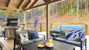 Un espace extérieur abrité avec un barbecue, un canapé et une table où sont servis des en-cas.