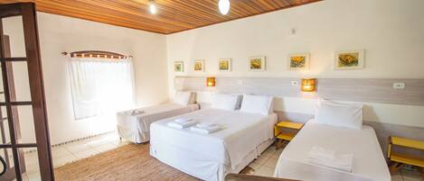 A hotel room with two beds, a wooden ceiling, and artwork on the walls.