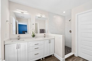 A modern bathroom with a white vanity, two sinks, a large mirror, and a shower area. - Super Luxe- Sleeps 17 W Designs Near Disney (Kissimmee)