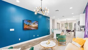 Una sala de estar moderna con una pared azul de acento, un comedor y una cocina.