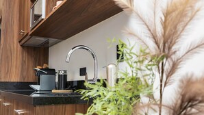 Eine moderne Küche mit Holzschränken, einer Edelstahl-Spüle und einer Kaffeemaschine.