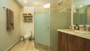 Ein modernes Badezimmer mit einer gläsernen Duschkabine, einer Toilette und einem Waschtisch mit Spiegel.