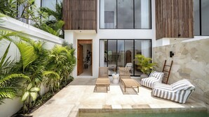 A modern outdoor living area with a pool, lounge chairs, and tropical plants. - Villa JB Canggu (Canggu)