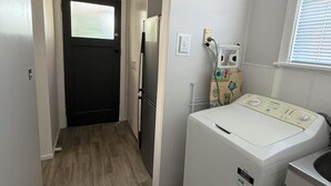 A laundry room with a washing machine, dryer, and a refrigerator. - Kowhai on Douglas – Your Relaxing Escape (Levin)