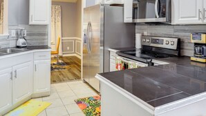 Una cocina moderna con armarios blancos, electrodomésticos de acero inoxidable y encimera de mármol.