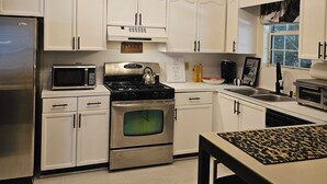 A modern kitchen with white cabinets, stainless steel appliances, and a black countertop. - PriMary EVolution Properties ~ Atlanta - convenient, comfy, chic 3 bedroom home  (Atlanta)