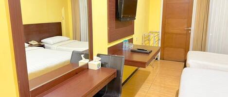 A hotel room with two beds, a desk with a chair, a television mounted on the wall, and a door.