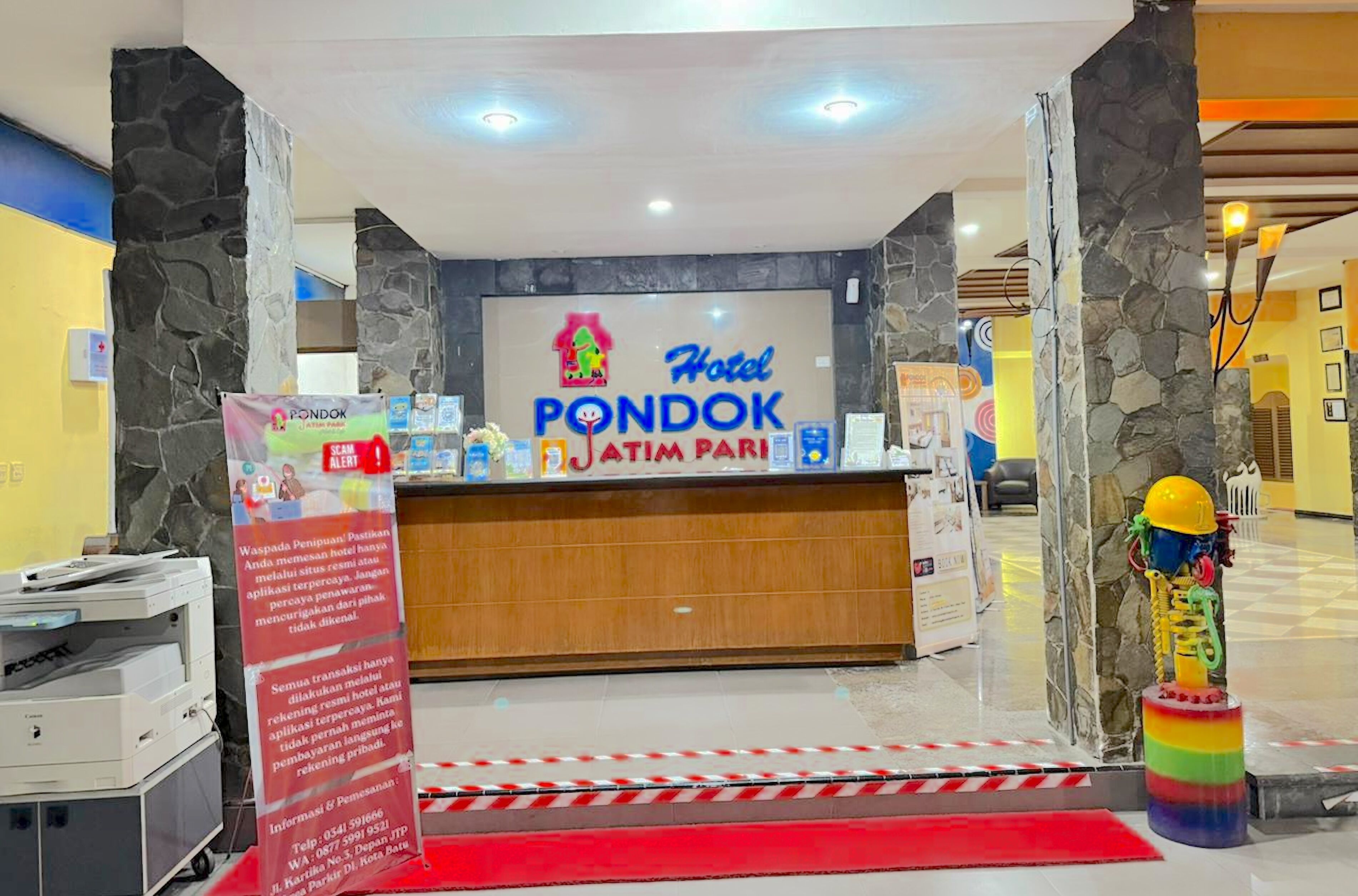 A reception desk with a sign for 'Hotel Pondok Atim Pari'.