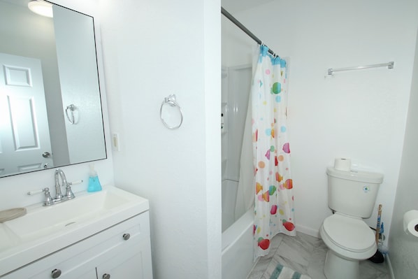 A bathroom with a white sink, mirror, and toilet.