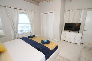 A bedroom with a bed, a television on a dresser, and a closet.